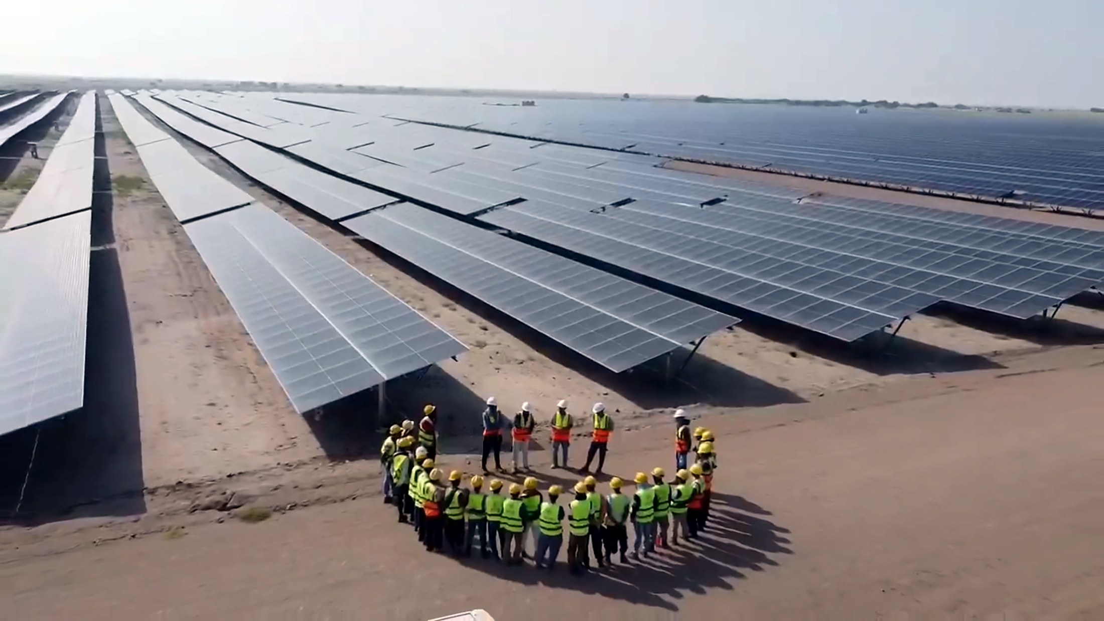 UVEC engineers and site crew in a briefing circle at a completed solar plant