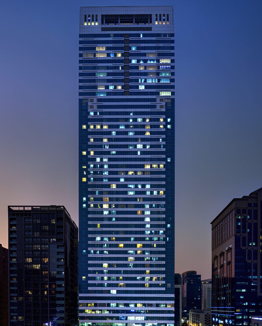 A high-rise office tower in Abu Dhabi lit at dusk