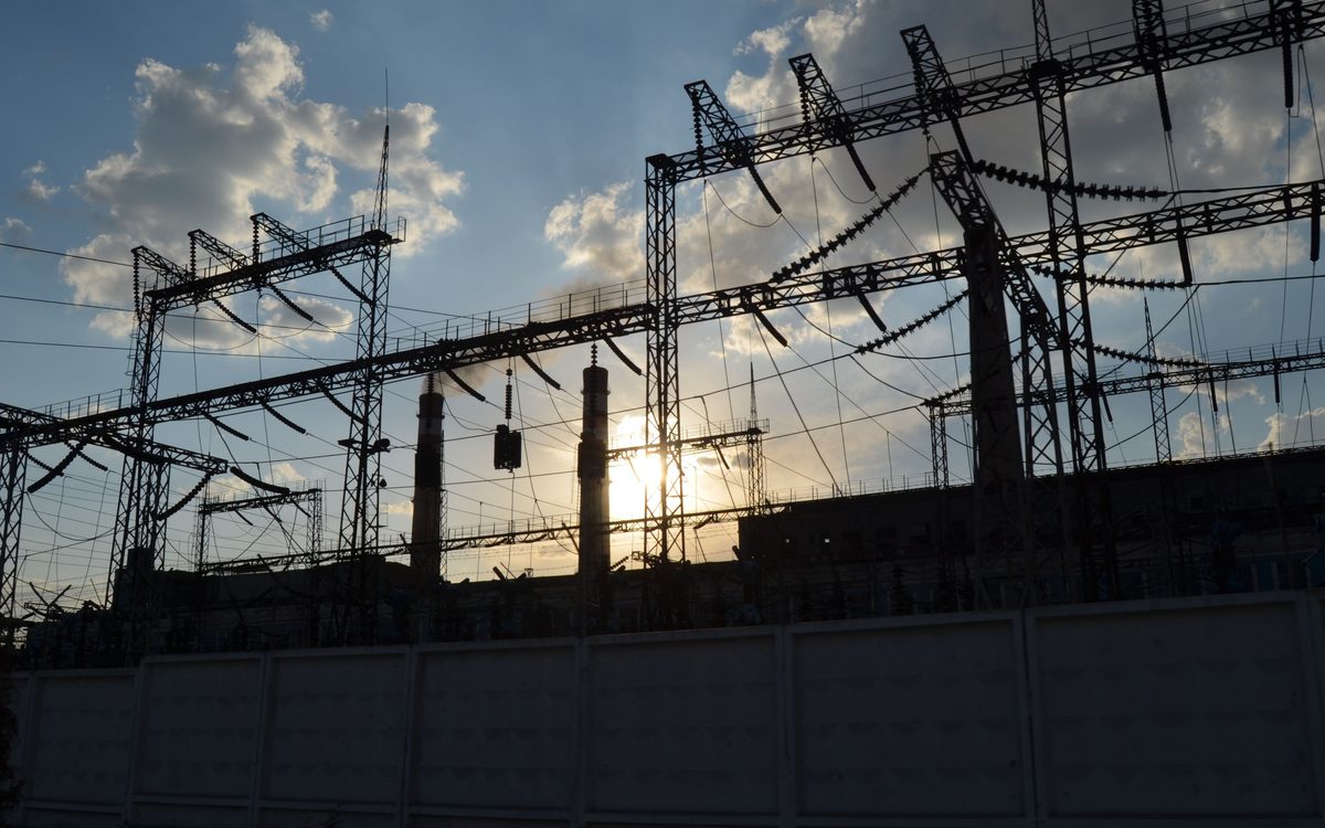 High-voltage busbars and gantries at a transmission substation at sunset