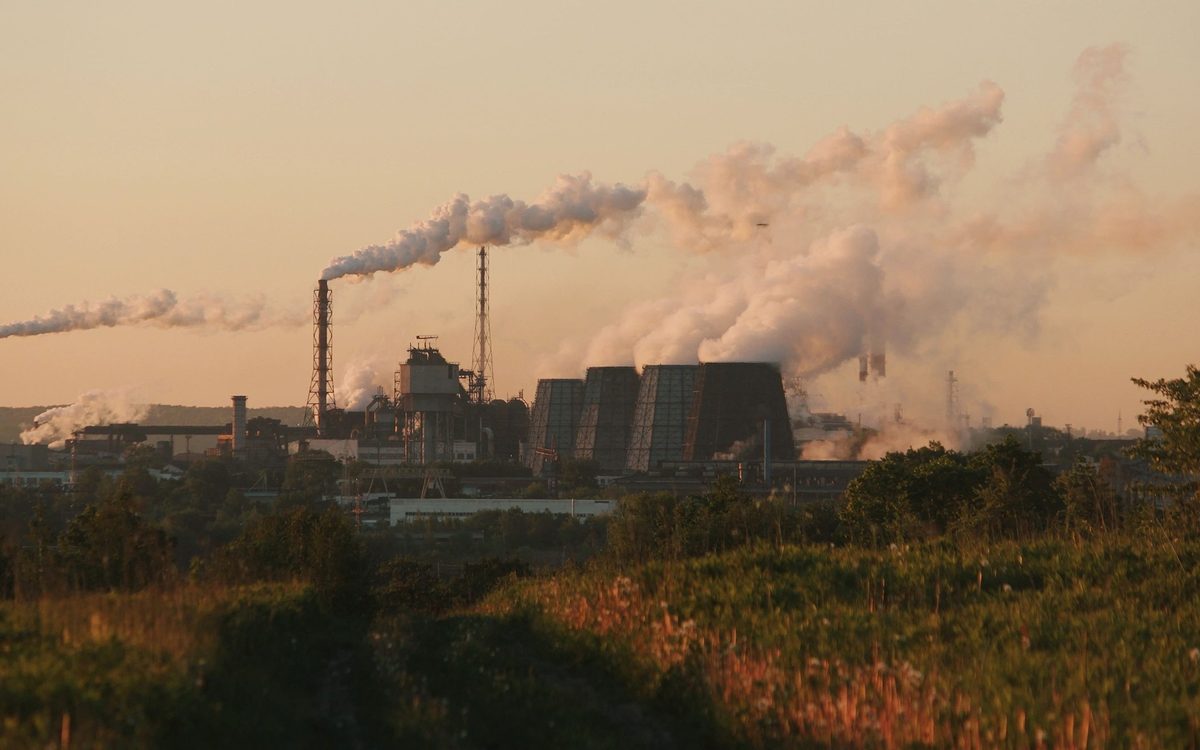 A thermal power plant at dusk with steam rising from its stacks
