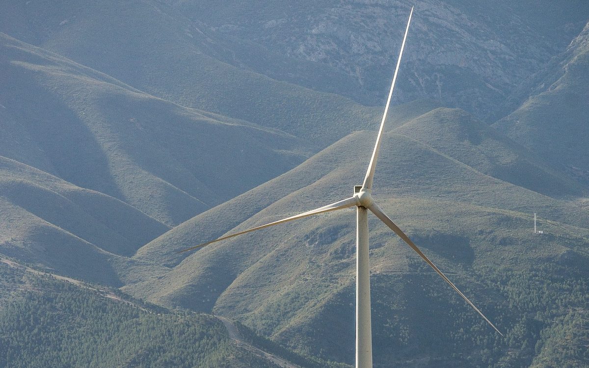 A wind turbine on a hillside above a valley