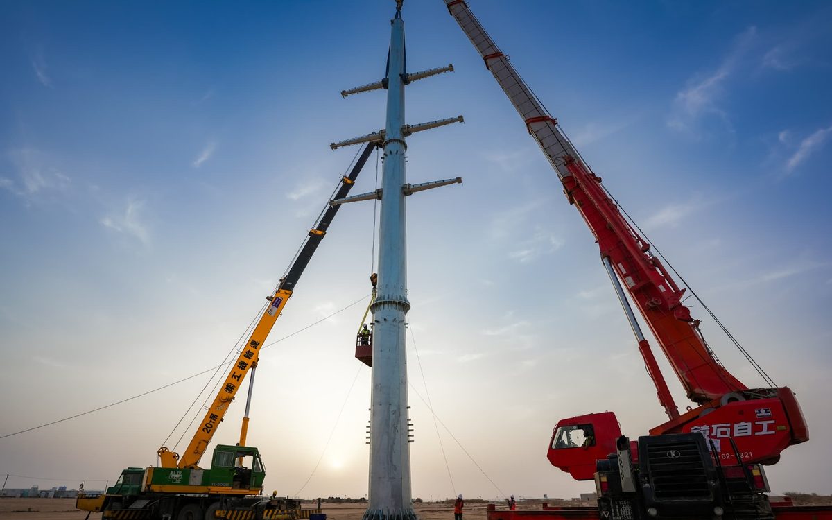 Two cranes lifting a steel transmission tower section into position on the Bir Ahmed to Hiswa line