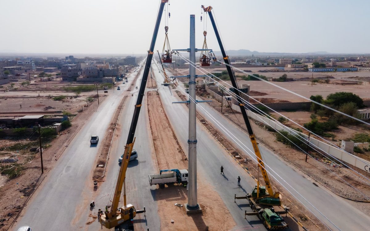 Cranes erecting the Mocha overhead line towers beside a road