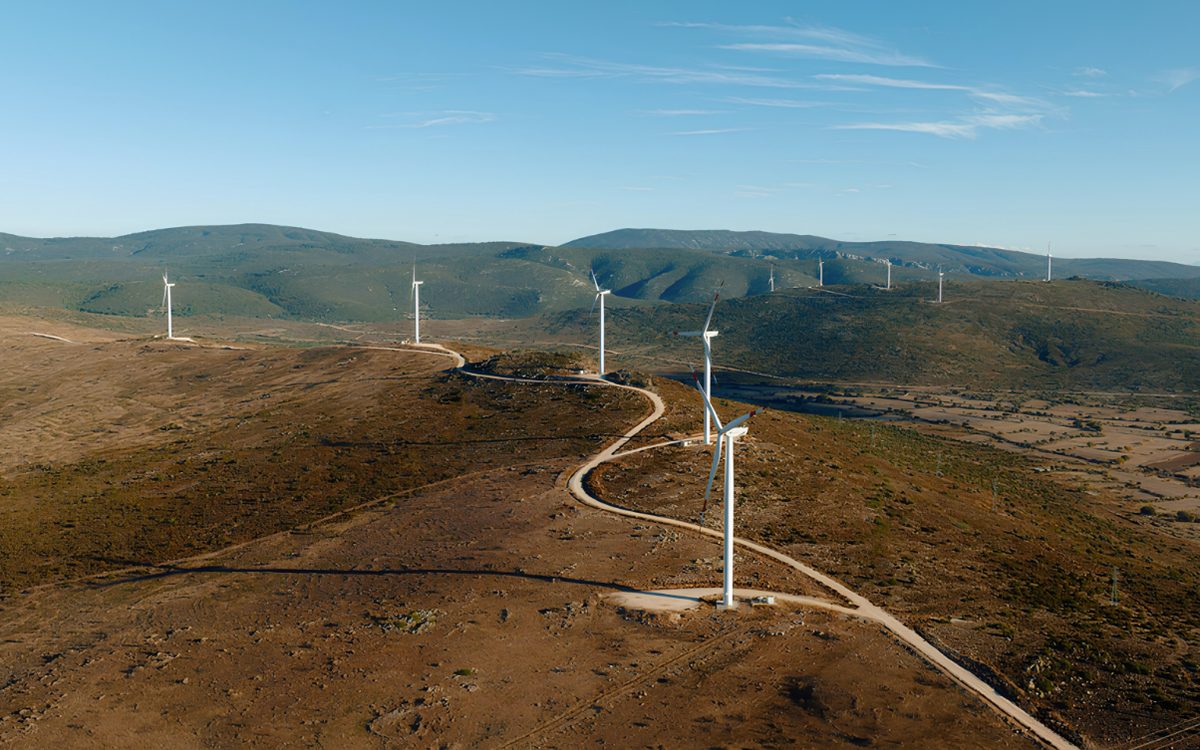 A wind turbine on a ridge above a hillside access road