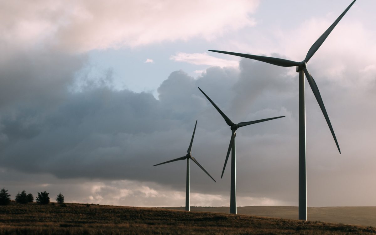 Three wind turbines in a row beneath heavy grey cloud