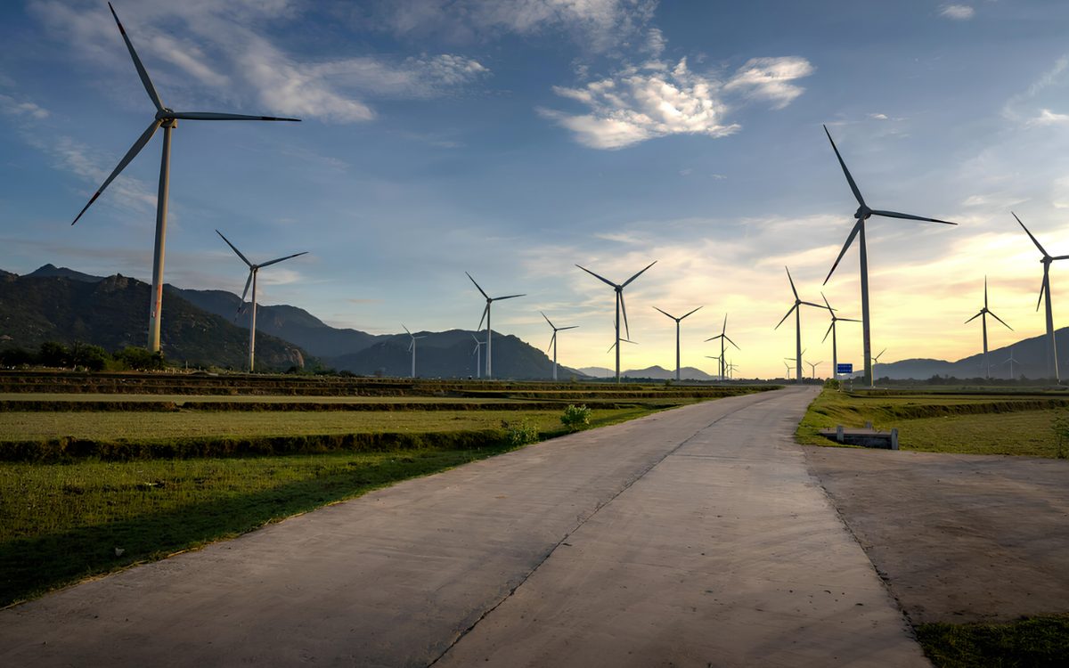 A road running between rows of wind turbines at dusk