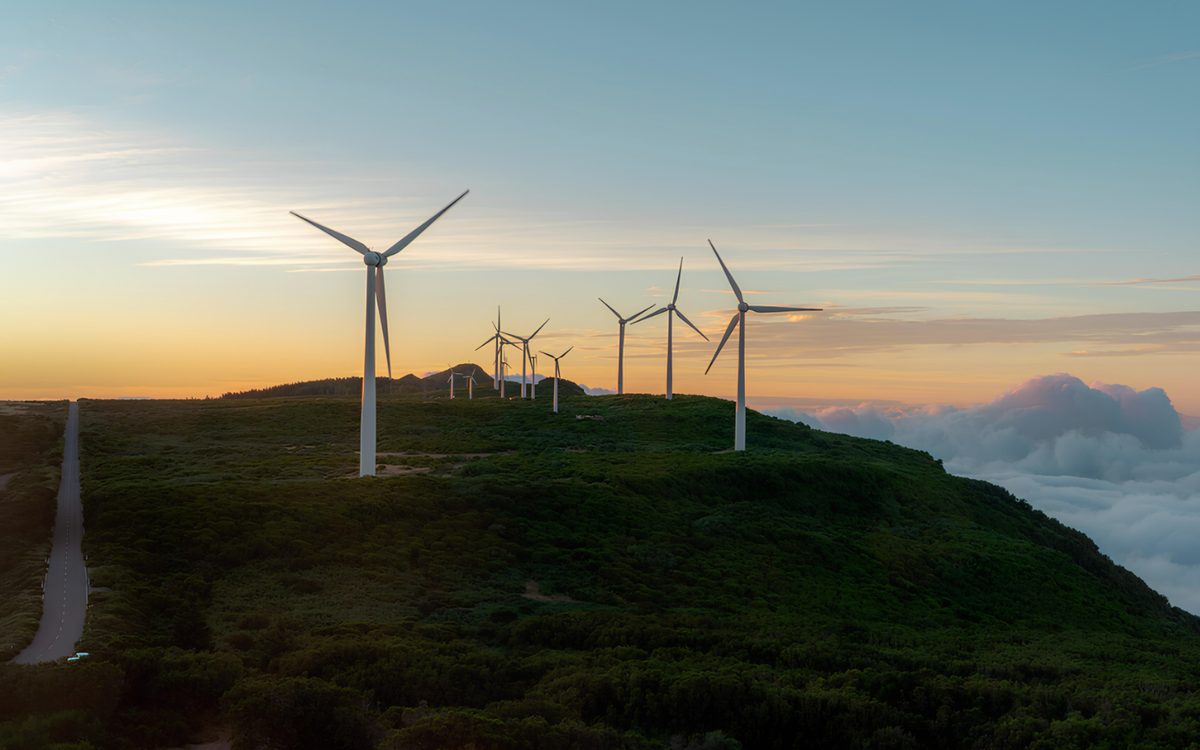 Wind turbines on a green hilltop above low cloud