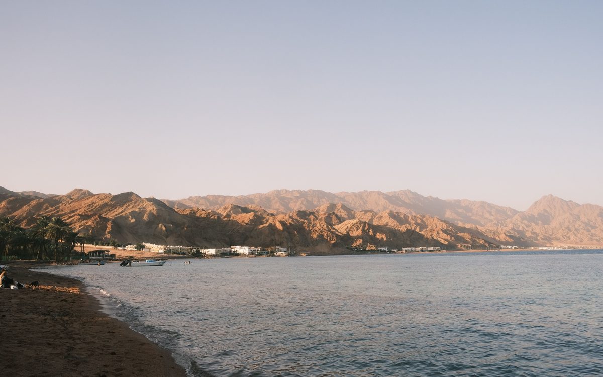The coastal site of the Ibn Sina power plant, mountains rising behind the shoreline