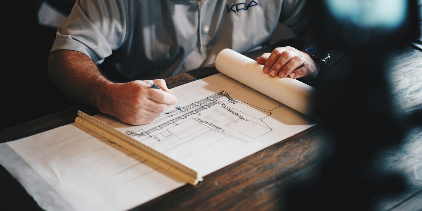 An engineer drafting a technical drawing with a scale ruler