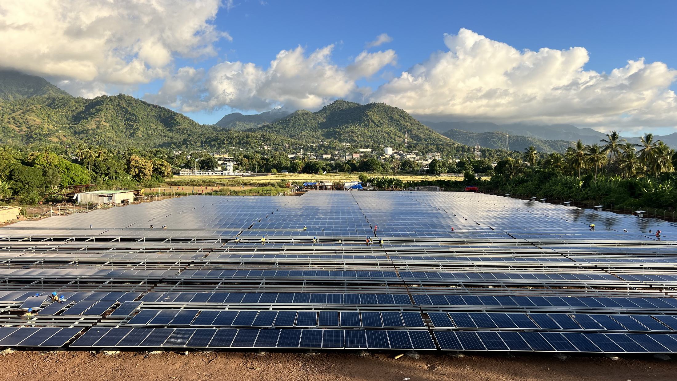 The Anjouan solar plant under construction on Comoros, with the town and green mountains behind it