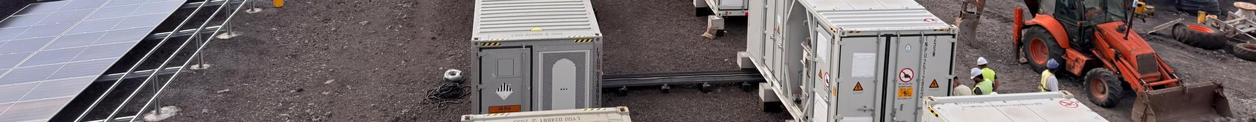 Battery storage containers alongside a solar array under construction