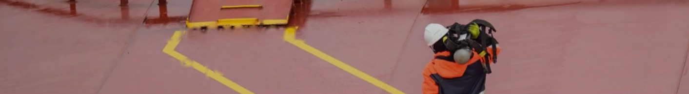 A field technician in protective gear on a red industrial deck