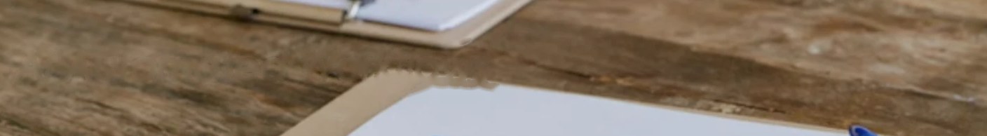 A clipboard and papers on a wooden desk