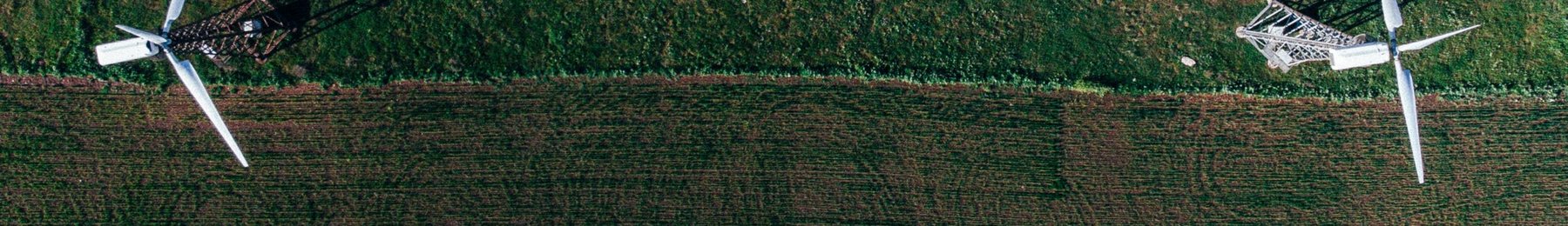 Aerial view of wind turbines beside a green field