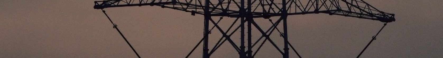 A transmission tower silhouetted against an evening sky