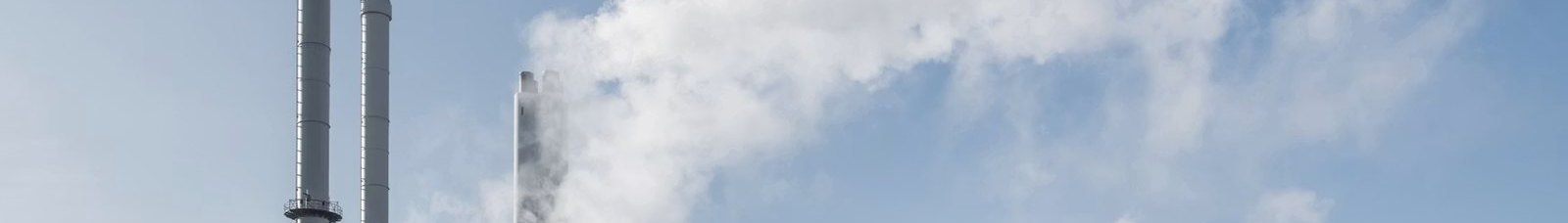 Power station stacks releasing white plumes against a blue sky